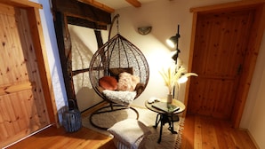 A cozy room with a hanging chair, a small table with a lamp, and a wooden floor. - 4 star holiday home "Zum Weiher" 160sqm in the heart of the Hunsrück-Hochwald National Park  (Allenbach)
