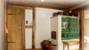 A rustic room with wooden floors, a wooden door, a white wall with a green tiled section, and baskets on a table. - Deluxe farmhouse, smokehouse kitchen, tiled stove, bathroom in stable, Whirlpool (Bubsheim)