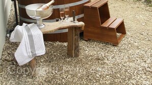 A wooden barrel with a metal band, a metal bowl, and two glasses on a wooden bench outside a building with a tiled roof. - Deluxe farmhouse, smokehouse kitchen, tiled stove, bathroom in stable, Whirlpool (Bubsheim)