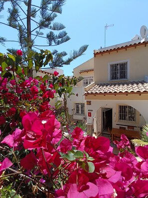 A building with a tiled roof, a balcony, and a door leading to an interior space.