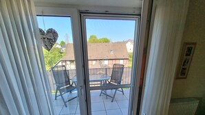 Una stanza con una porta scorrevole in vetro che dà su un patio esterno con tavolo e sedie.