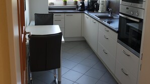 Una cucina moderna con mobili bianchi, un piano di lavoro nero e un forno integrato.