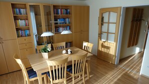 Zona pranzo con tavolo e sedie in legno, circondata da librerie.