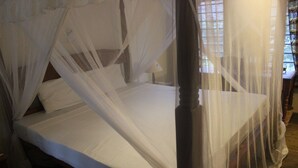 A four-poster bed with white linens and a canopy.
