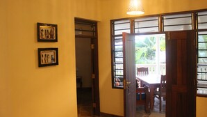 A hallway with a wooden door, a ceiling fan, and two framed pictures on the wall.