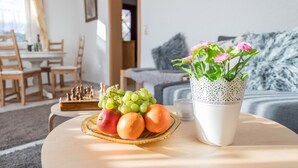 A dining table with a fruit plate, a vase with flowers, and a chessboard. - Vacation home with pet-friendly large fenced garden in Bad Tabarz. (Tabarz/Thüringer Wald)