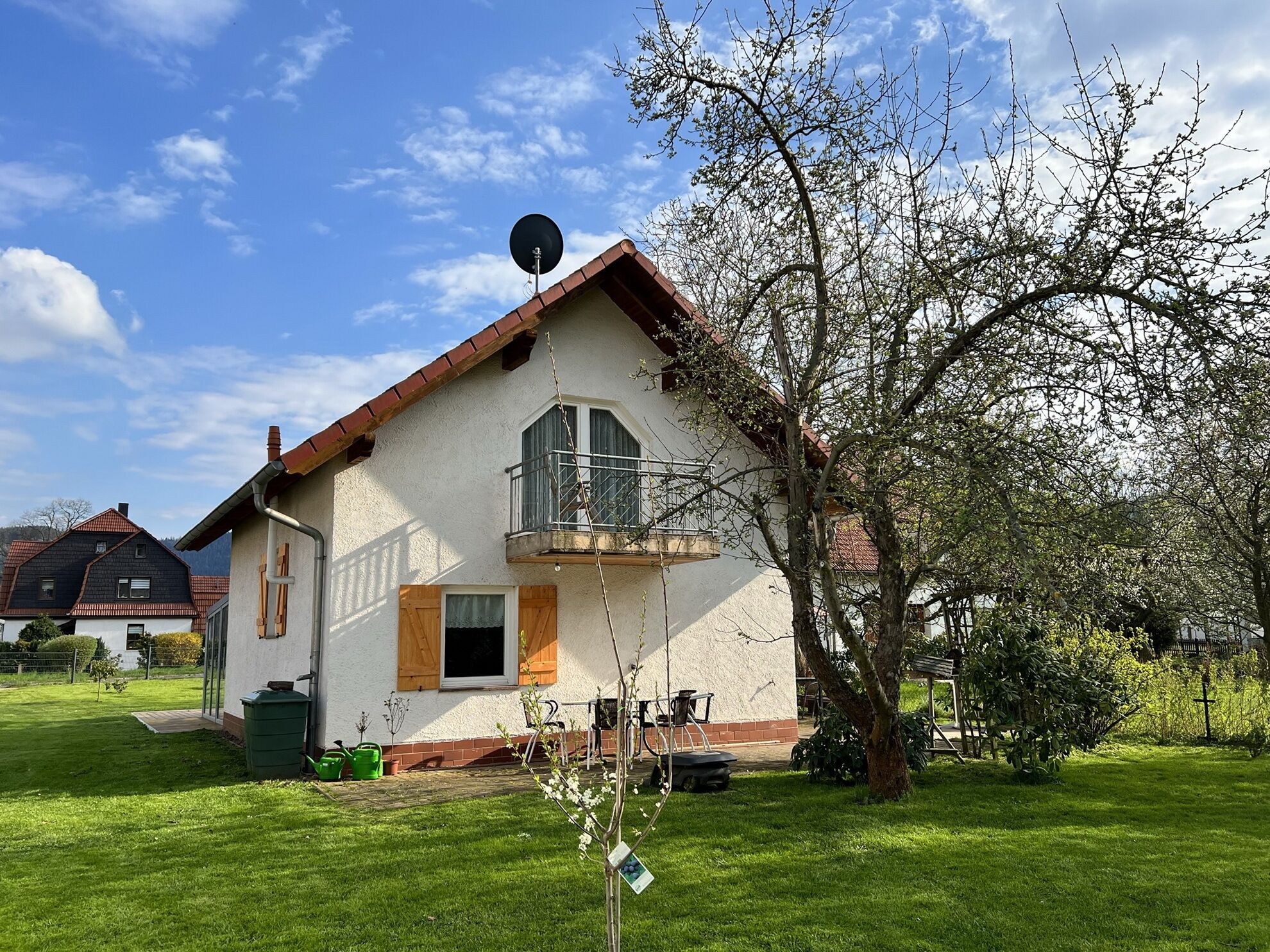 Une maison à deux étages avec un balcon, une antenne parabolique et une pelouse bien entretenue.