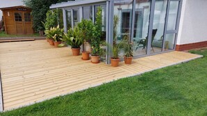 A wooden deck with potted plants, a glass door, and a small wooden structure labeled "Toblerer Strasse". - Vacation home with pet-friendly large fenced garden in Bad Tabarz. (Tabarz/Thüringer Wald)