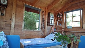 L’intérieur d’un chalet en bois, avec un lit, une fenêtre et une horloge.