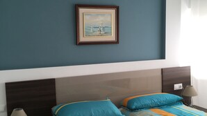 Un dormitorio con una cama, una mesita de noche, una lámpara y un cuadro en la pared.