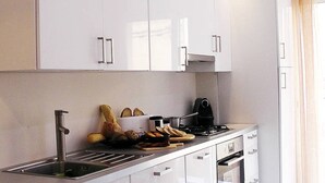 Eine moderne Küche mit weißen Schränken, einer Edelstahl-Spüle, einem Herd und einem Toaster.