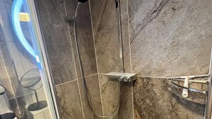 A bathroom with a glass-enclosed shower, marble walls, and a white sink. - Newly furnished apartment with a large terrace (Ostseebad Boltenhagen)