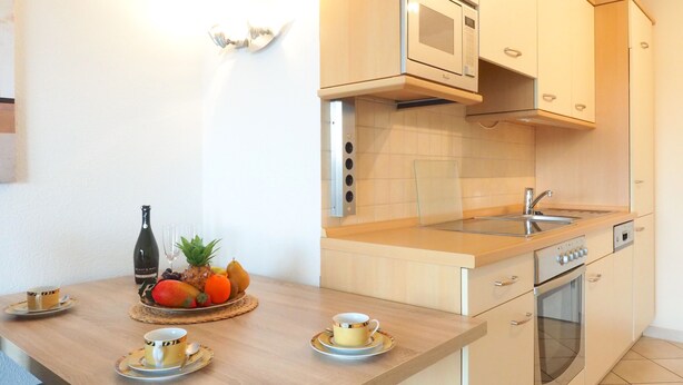 A modern kitchen with a microwave, oven, and sink. There is a fruit bowl on the counter and a bottle of wine. - Newly furnished apartment with a large terrace (Ostseebad Boltenhagen)