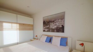 A bedroom with a large bed, a nightstand with a lamp, and a wall-mounted picture. - Newly furnished apartment with a large terrace (Ostseebad Boltenhagen)