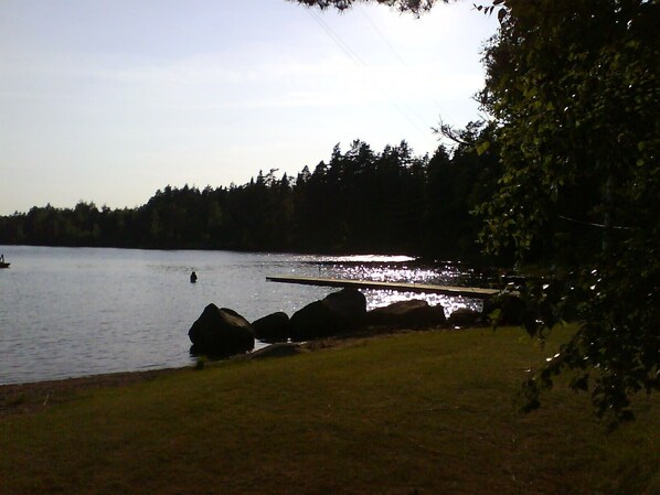 A lakeside view with a dock extending into the water, surrounded by rocks and trees. - Byn med lugn, natur och sjöar, bastu (Lammhult)