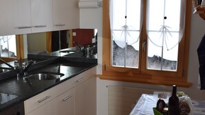 A kitchen with a double sink, a stove, and a window with curtains.