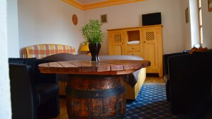 A room with a wooden table, a sofa, a cabinet, and a television. - Apartment for 2 pers. with a view of Mildenstein Castle (Leisnig)