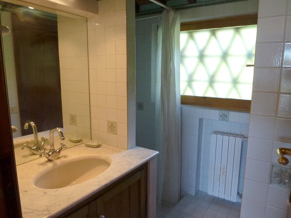 A bathroom with a sink, two faucets, a mirror, and a window with a geometric pattern.