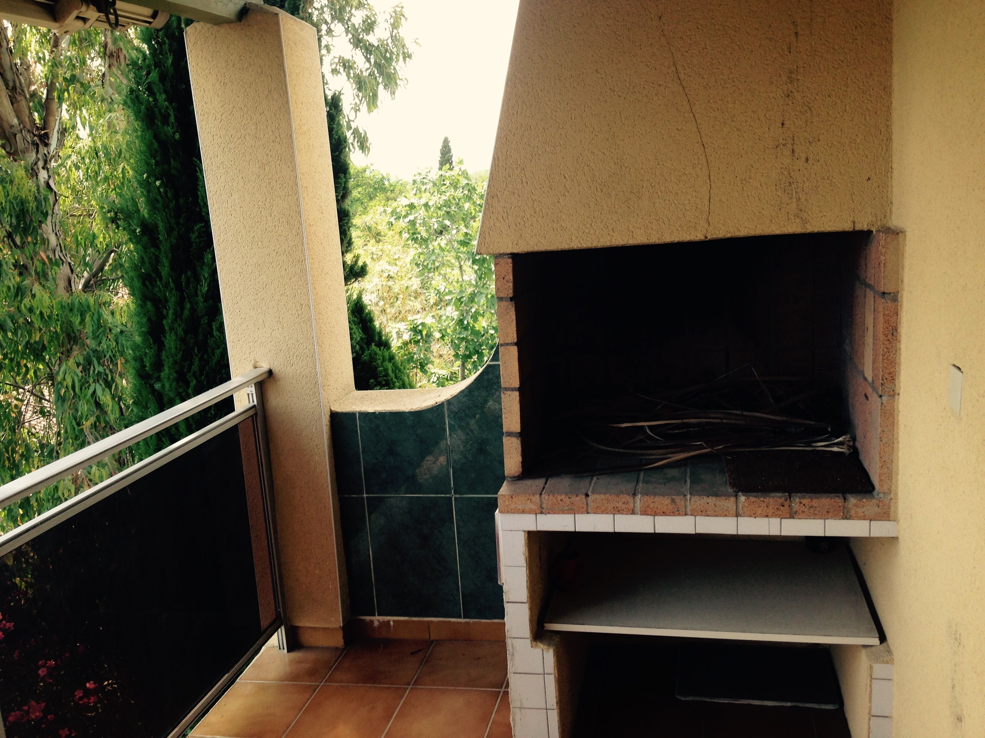 A brick-built outdoor oven with a tiled floor and a metal railing.