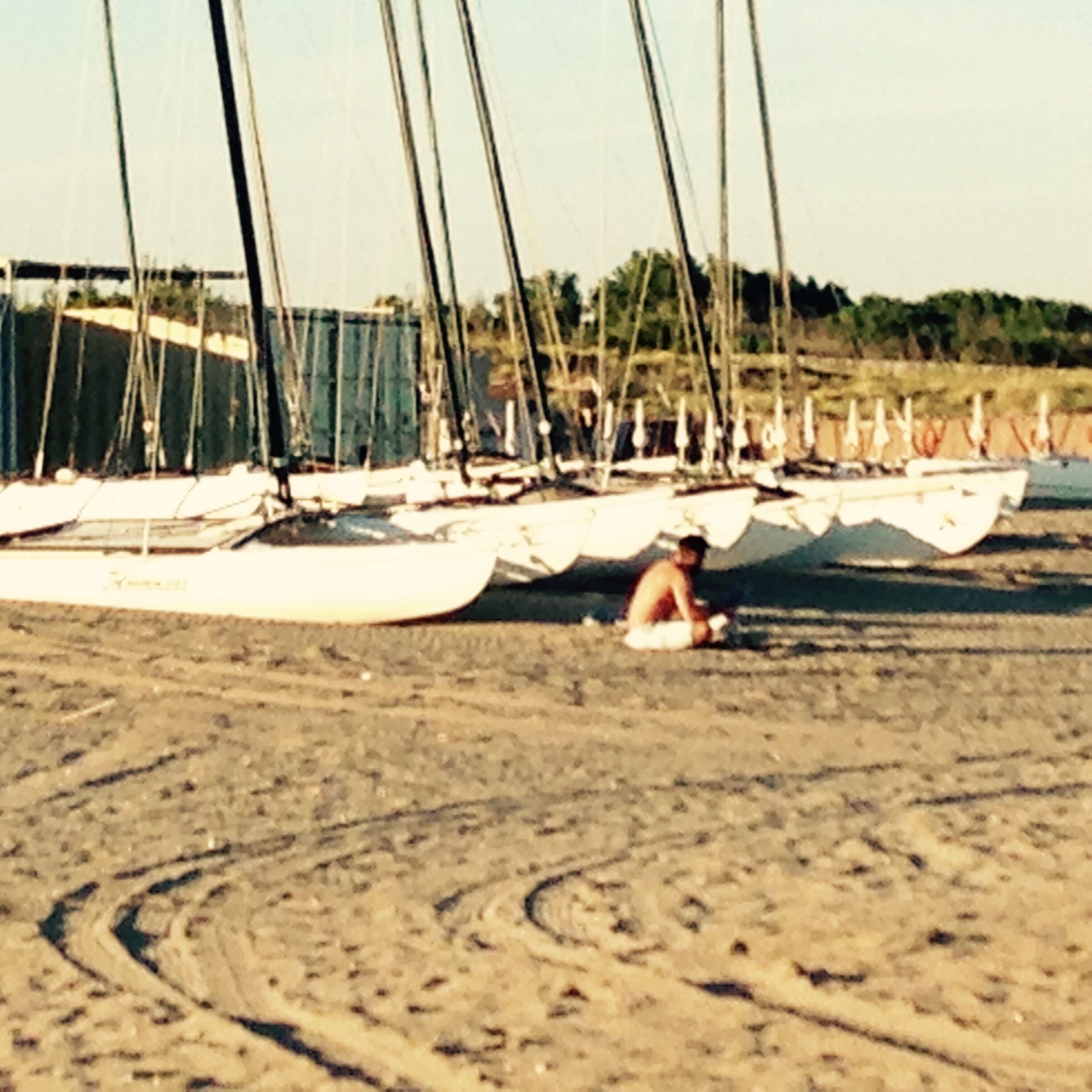 Ein sandiger Strand mit mehreren vor Anker liegenden Segelbooten.