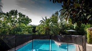 A rectangular swimming pool with a black fence, surrounded by lush greenery and a palm tree. - Superb villa with sea view, all mod cons,pool and private garden, Wifi (Portiragnes)