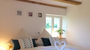 A neatly made bed with striped bedding and decorative pillows, a bedside lamp, and a window with a plant on the windowsill. - Welcome to the Allgäu family Berger (Sulzberg)