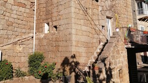 Un edificio de piedra con diseño tradicional, que presenta una pequeña entrada y una escalera que conduce a la puerta principal.