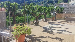 Un patio con muro de piedra, plantas en macetas y una farola.