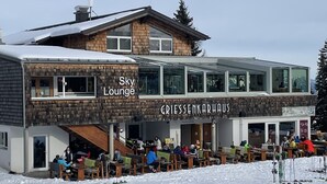 Een skigebouw met terras en een bordje met de tekst 'Sky Lounge'.