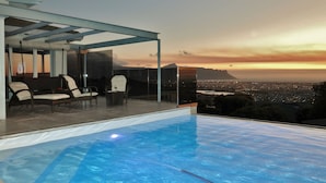 Une piscine à débordement offrant une vue imprenable sur le paysage urbain au coucher du soleil.