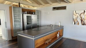 Une cuisine moderne dotée d’un îlot central, d’appareils électroménagers en acier inoxydable et d’une armoire en bois.