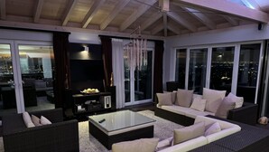 Un salon moderne avec un grand canapé d’angle, une table basse en verre et une cheminée.