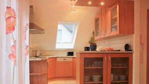A kitchen with wooden cabinets, a toaster, a sink, and a window. - 3-star vacation apartment on the Rheinsteig with a magnificent view over the Rhine Valley (Rüdesheim am Rhein)