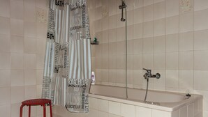 A bathroom with a bathtub, a shower, and a red stool. - Beautiful apartment in a central location in Wedel (Hamburg) (Wedel)