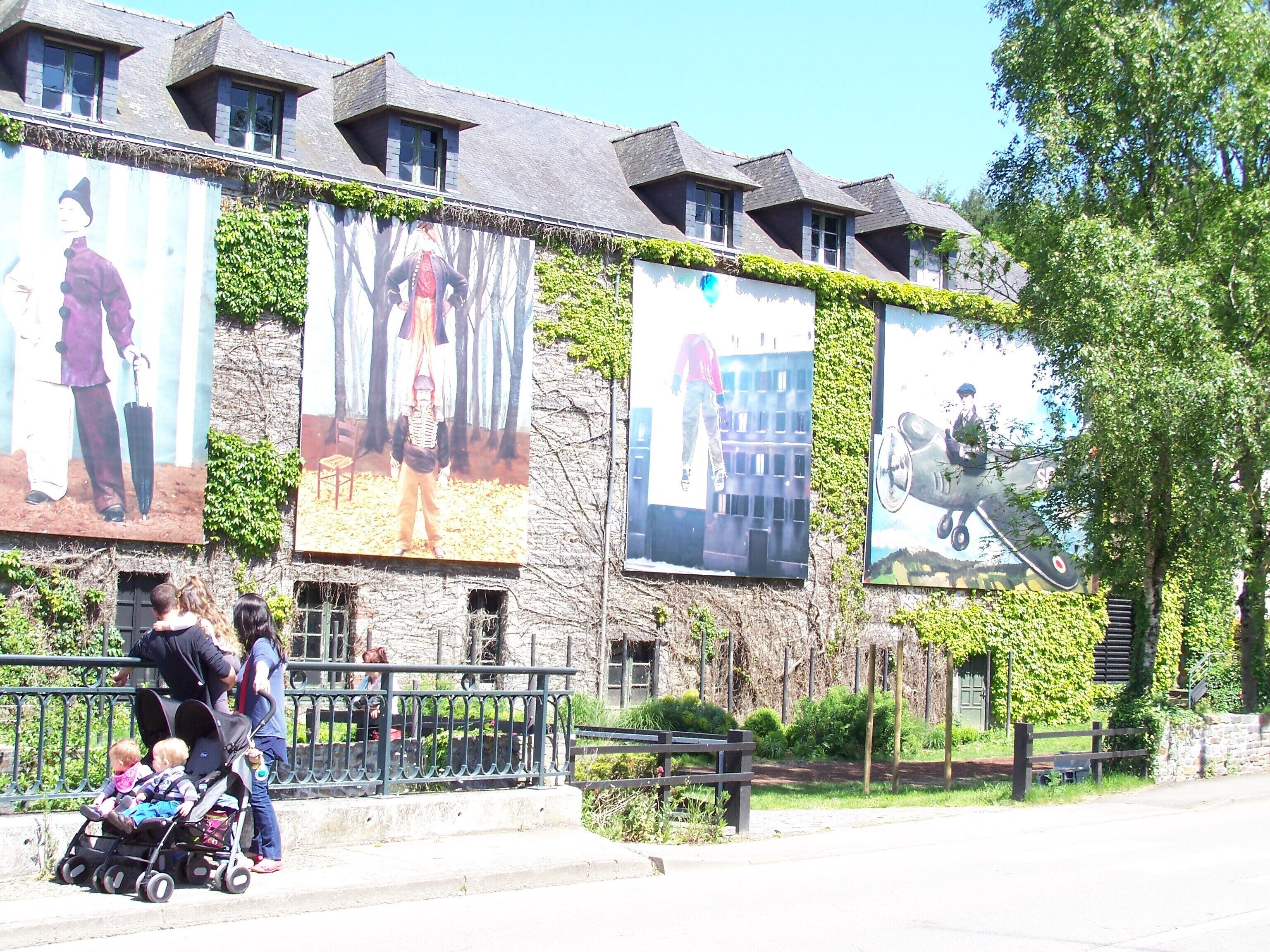 A building with large murals on its side, a paved walkway, and a metal fence.
