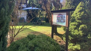 Ein hölzernes Schild mit einem Gebäude und einem Rasen im Hintergrund.