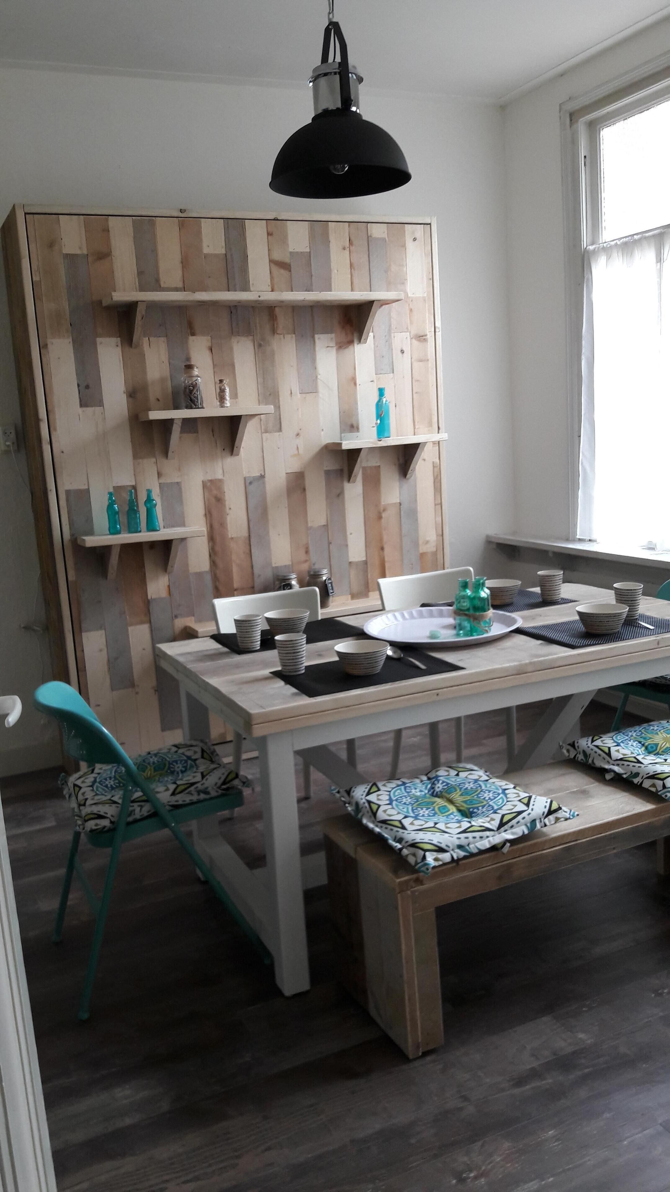 A dining area with a wooden table, chairs, and a hanging light fixture.