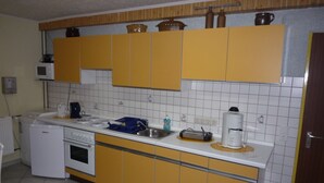 A kitchen with yellow cabinets, a white countertop, a coffee maker, and a microwave.