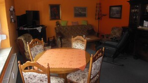 A living room with a round table, floral chairs, a sofa, and a television.