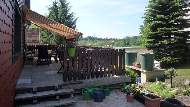 A patio with outdoor furniture, a wooden fence, and potted plants.
