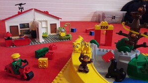 Un set de jocs LEGO amb una casa petita, un tobogan i diverses figures d'animals.