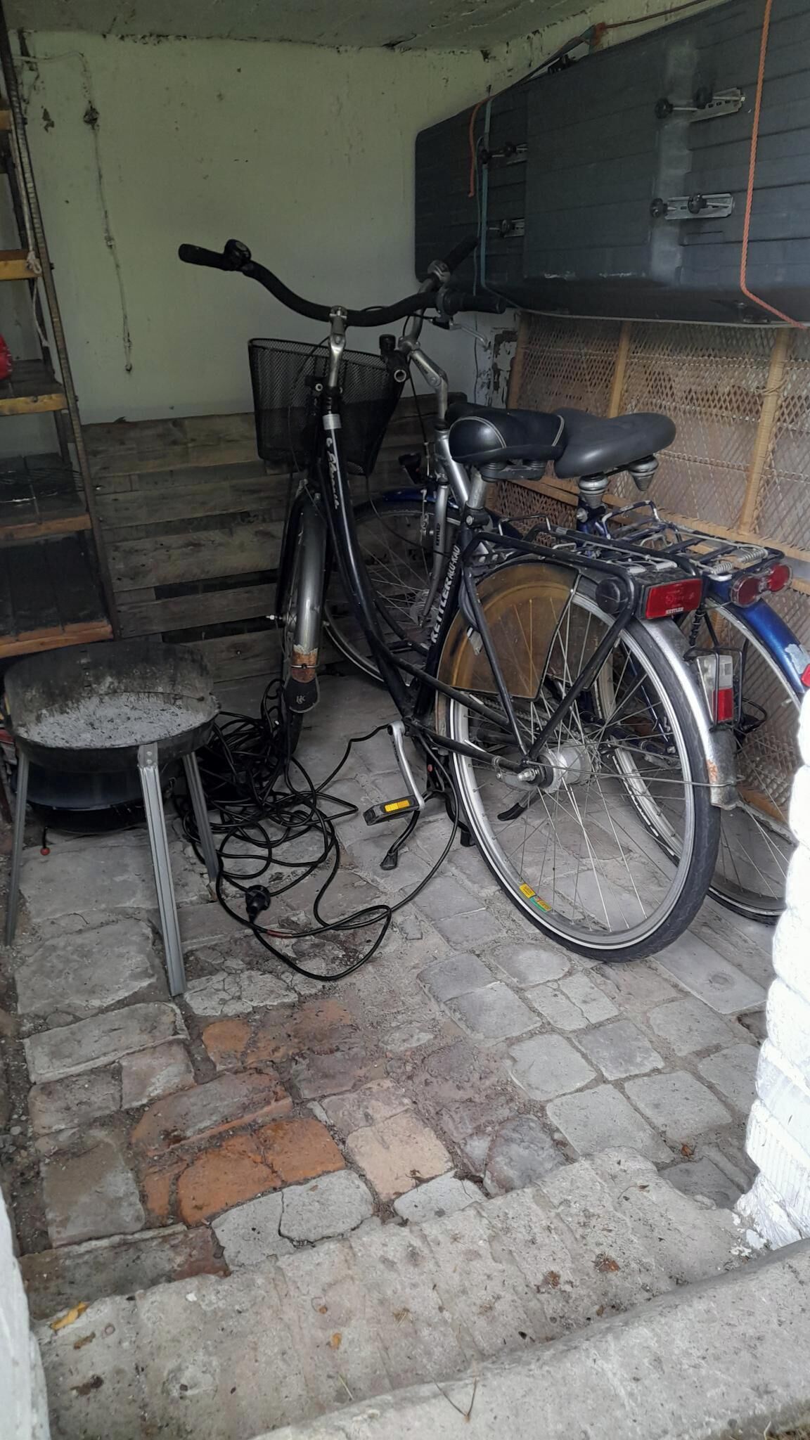 Een fiets geparkeerd in een garage, met een werkbank en gereedschap in de buurt.