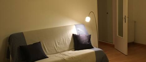 A room with a sofa, a lamp, and two framed pictures on the wall.