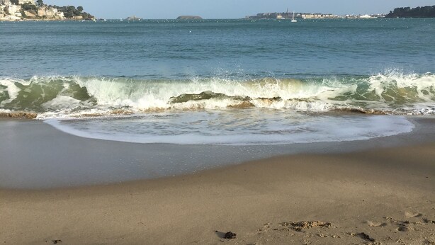Una spiaggia con impronte sulla sabbia e onde che si infrangono a riva.
