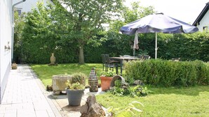 A patio area with a table and chairs, surrounded by potted plants and a large umbrella. - Detached holiday home, Apartment 2 / for 2-4 persons, W-LAn free (Mehren)