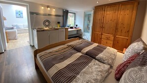 Ein Schlafzimmer mit einem großen Bett, einem Holzschrank und einer Küchenzeile.