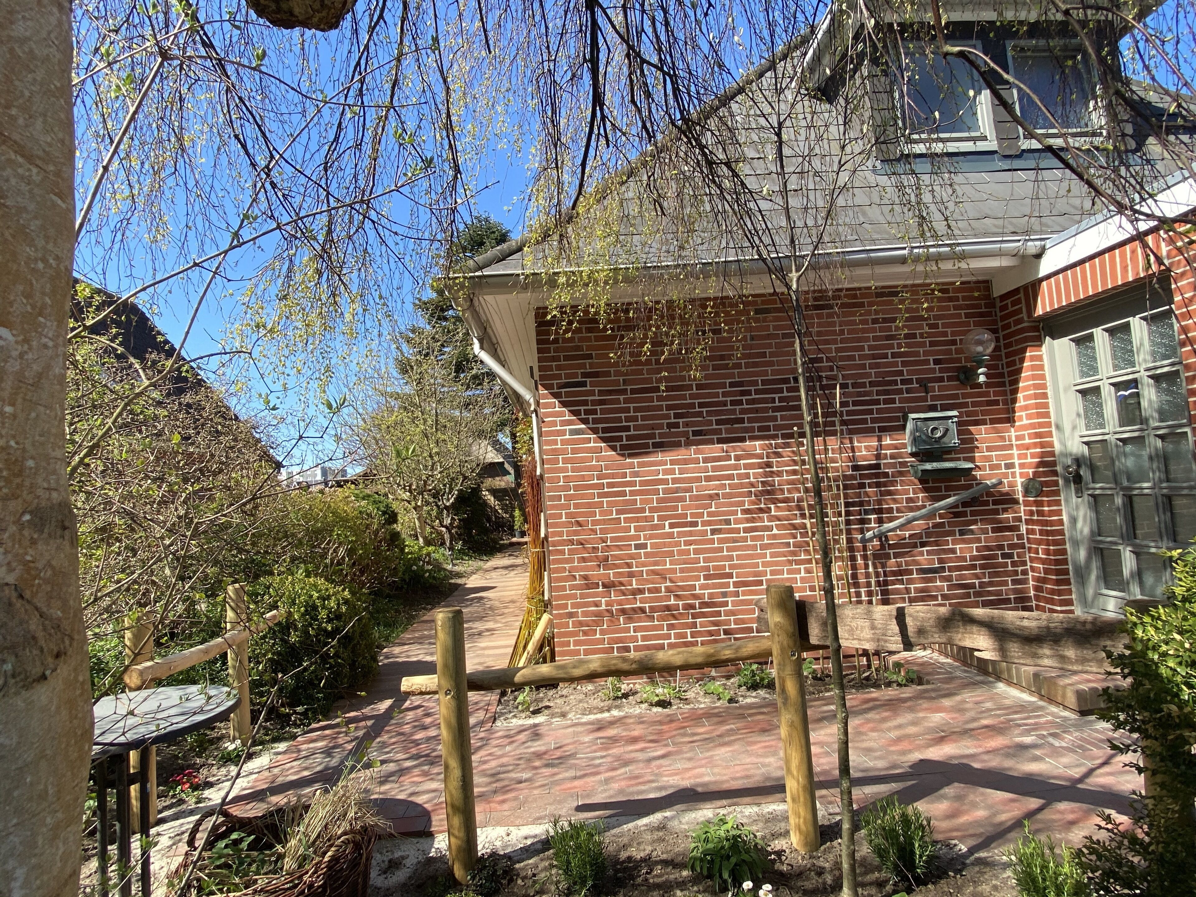 A brick building with a wooden door and a window. There is a brick pathway leading to the entrance.