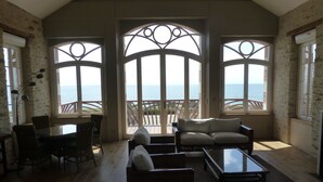 Une pièce spacieuse dotée d’une grande fen être donnant sur la mer, et aménagée avec un canapé, des fauteuils et une table.