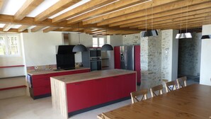 Une cuisine moderne avec des meubles de rangement rouges, une table à manger en bois et un mur décoratif en pierre.