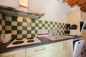 Una cocina con salpicadero a cuadros, un tostador, un hervidor, un microondas y un lavavajillas.